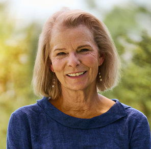 Head shot of Martha, a smiling woman in a dark blue sweater who lives with CIDP