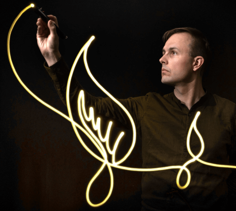Image of artist drawing so that the lines appear to glow like light. 